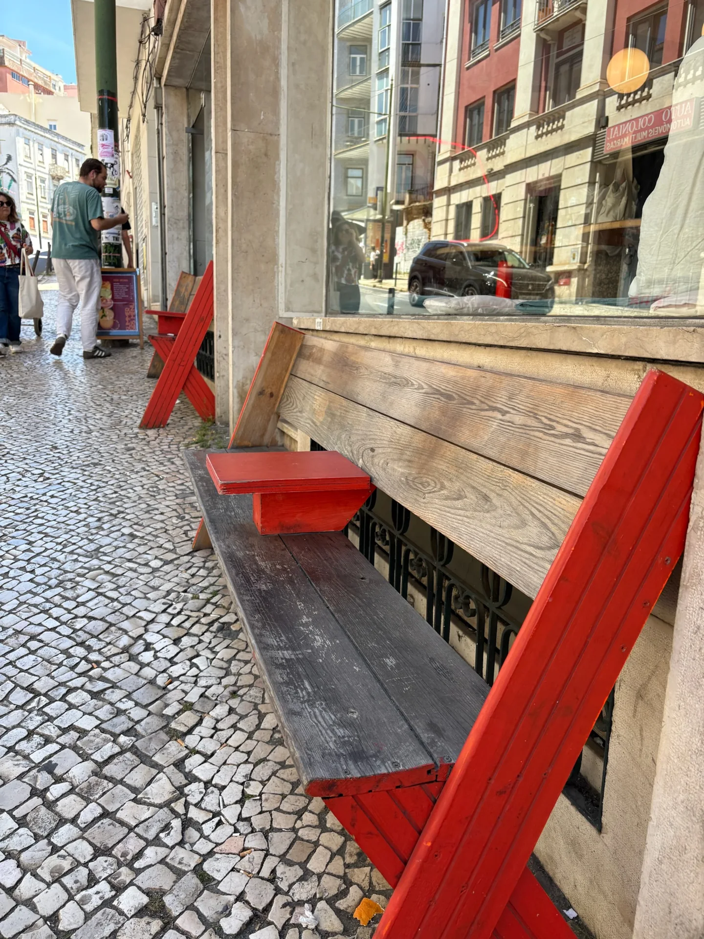 Red chairs and a wooden bench outside a Lisbon café