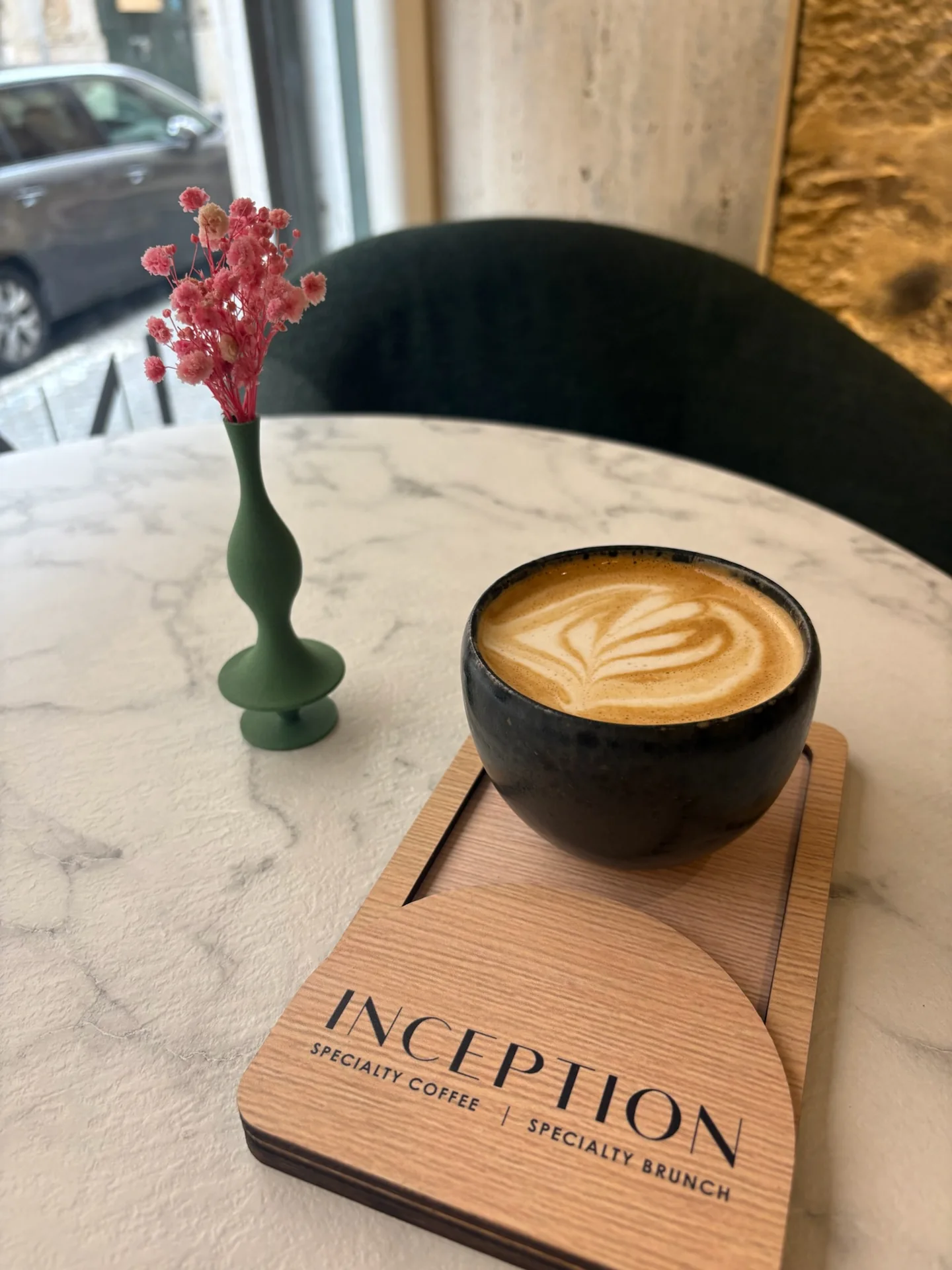 Two coffees and a small flower vase on a café table