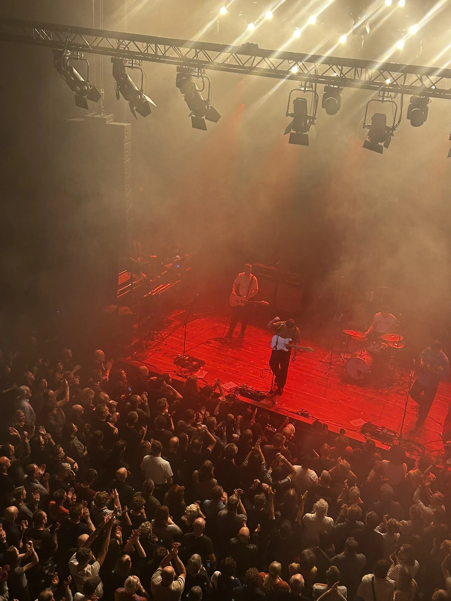 A crowd sharing a concert beneath red stage lights
