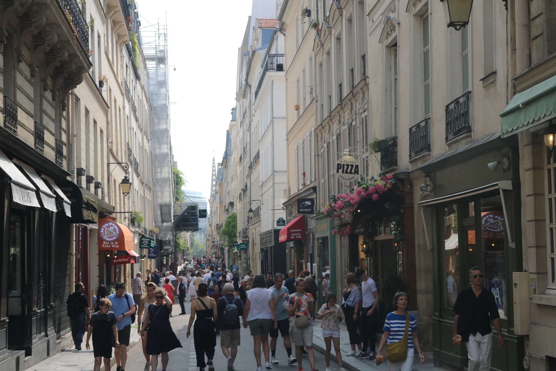 People walking along a café-lined street in Paris